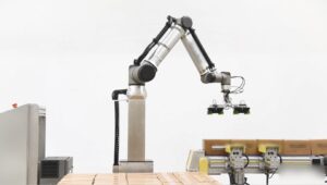 Ramię cobota Universal Robots na kolumnie podnoszącej, układające kartony na palecie