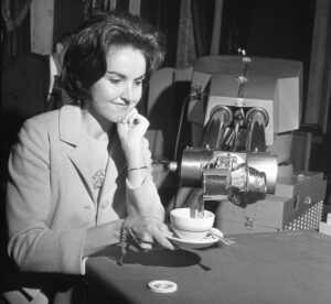 Ramię robota Unimate nalewa kawę do filiżanki, którą trzyma kobieta, podczas pokazu w hotelu Biltmore w 1967 roku