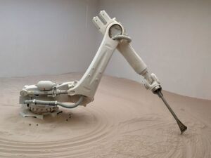 Ramię robota przemysłowego KUKA rysujące wzory w piasku